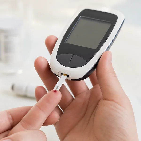 Glucometer testing at a fingertip in clinical light